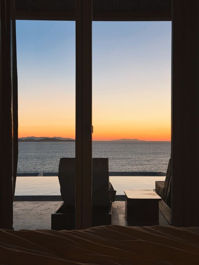 services-03 Breathtaking sunset from a luxury villa in Greece, overlooking the Aegean Sea with calm colors.