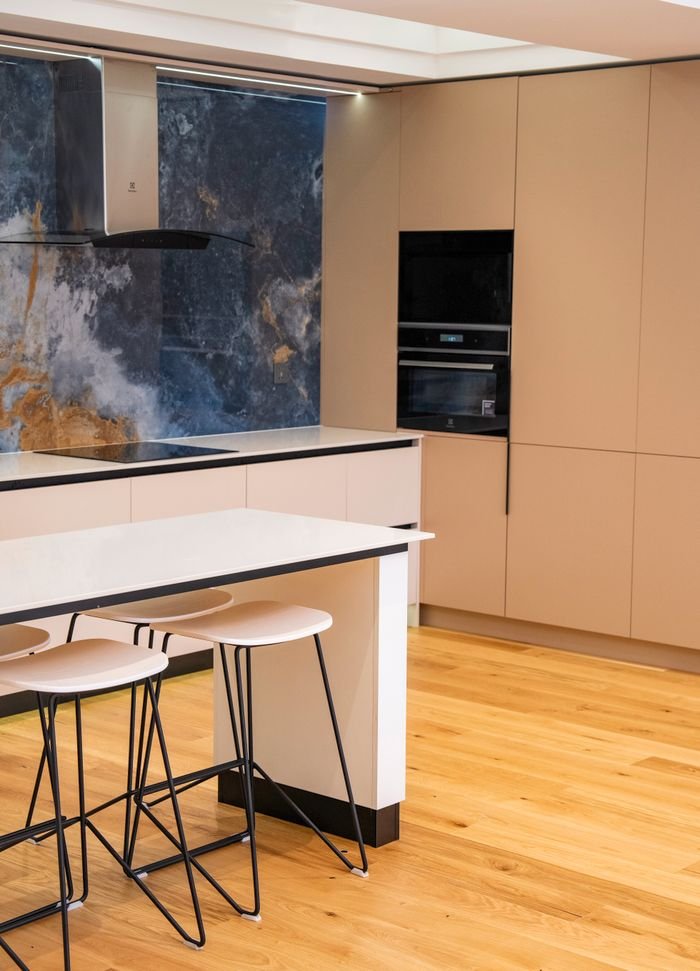 gallery-5 Sleek contemporary kitchen featuring marble backsplash, beige cabinets, and stylish bar stools.