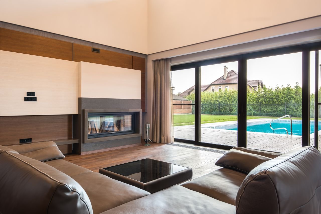 hero-img-02 Spacious modern living room with glass doors opening to a poolside area.